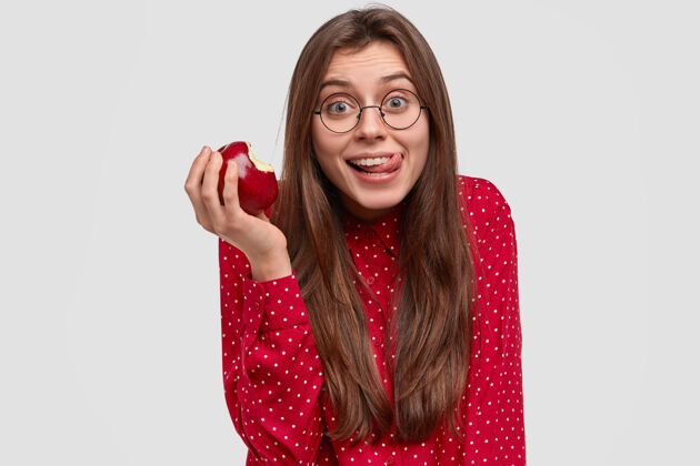 衬衫高兴的小姐吃着美味的苹果 快快乐乐地舔着嘴唇 有着幸福的表情保持咬健康