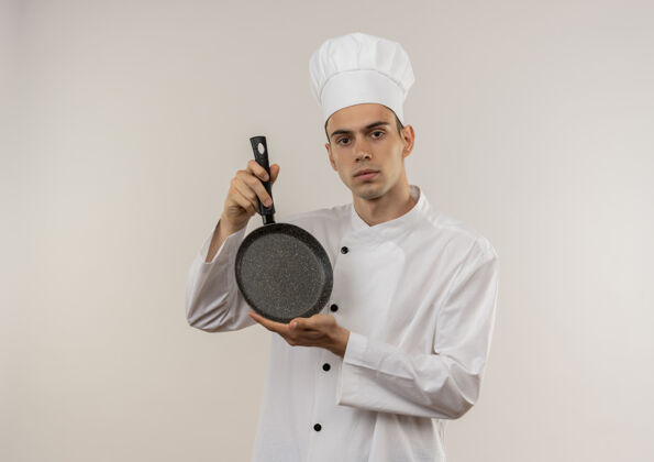 煎着年轻的男厨师穿着厨师制服 拿着煎锅站在隔离的白色墙壁上 有复印空间厨师拿着厨师