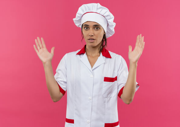 年轻年轻的女厨师穿着厨师制服 在隔离的粉红色墙上显示尺寸 并留有复印空间尺寸厨师外观