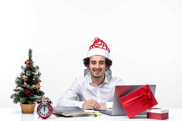 商人快乐积极的年轻商人与有趣的圣诞老人帽子庆祝圣诞节在白色背景的办公室电脑帽子庆祝