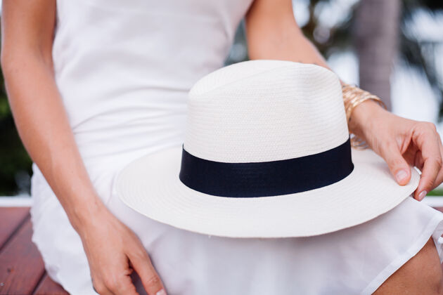 隐藏穿着丝绸合身连衣裙 戴着经典白帽子的近景女郎时尚配饰优雅