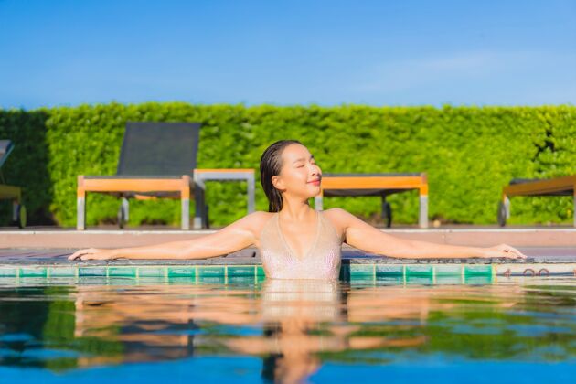 休闲美丽的亚洲年轻女子在度假酒店的室外游泳池周围放松的肖像女性苗条水疗