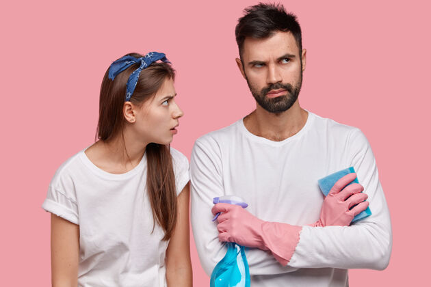 清洁不高兴的年轻欧洲女佣横拍神情疲惫地看着心烦的伴侣 双臂合十洗衣服家务海绵