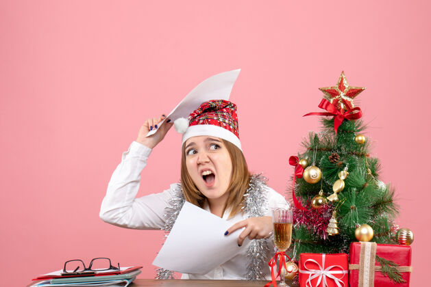 圣诞节年轻的女工拿着粉红色的证件文件帽子礼物