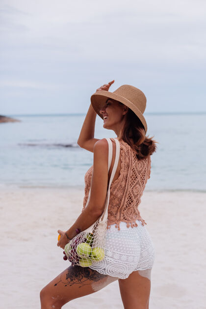肖像年轻漂亮的白种人 皮肤黝黑 穿着针织衣服 戴着帽子在沙滩上面料套装女士