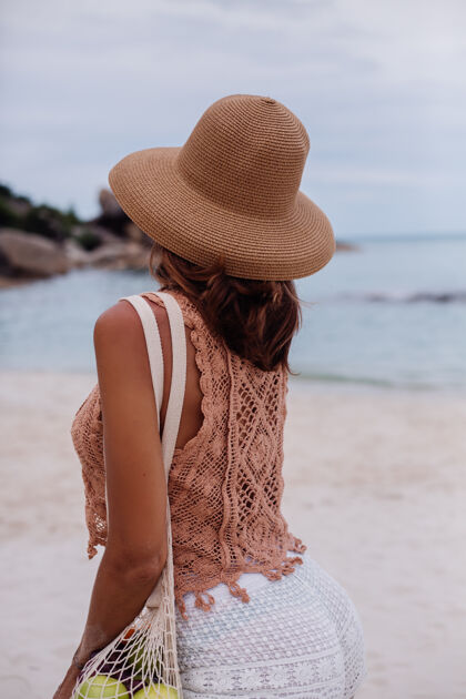 肖像年轻漂亮的白种人 皮肤黝黑 穿着针织衣服 戴着帽子在沙滩上手提包上衣成人