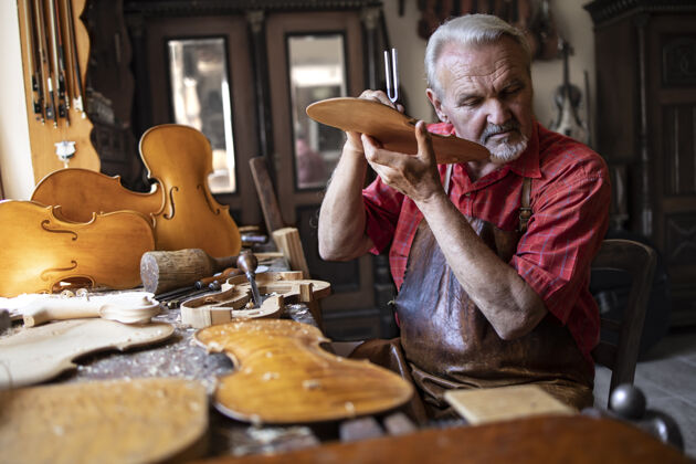 艺术高级木匠在他的老式木匠工作室里检查木材的音质手持工具压花