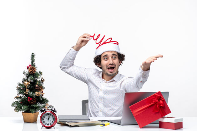 帽子新的一年的心情与惊讶微笑的年轻商人触摸他有趣的圣诞老人帽子在白色背景的办公室里的东西质问办公室商人车辆