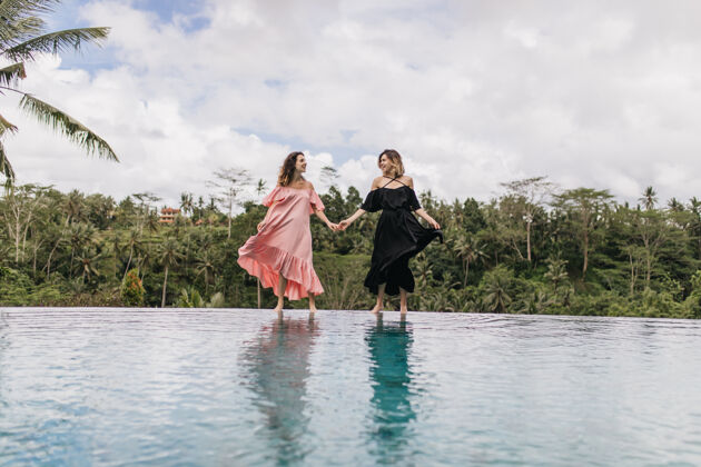 异国情调在湖边摆姿势时 漂亮的女人们在玩她的裙子女人们手牵手大自然的户外全长照片热带旅游活跃