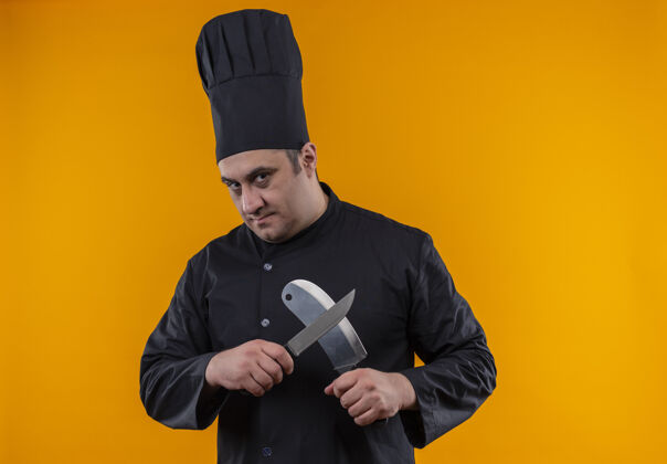 劈刀中年男厨师身着厨师制服 在黄色墙壁上用十字刀和菜刀 并留有复印空间中年长相交叉