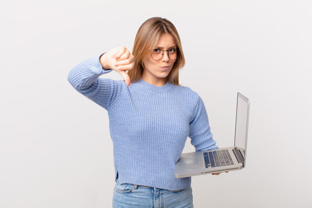 悲伤一个拿着笔记本电脑的年轻女人生气了 竖起大拇指成人硬件麻烦