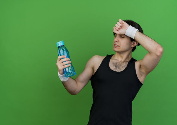 瓶子一个穿着运动服 戴着头巾 拿着一瓶水的年轻人看起来很累抱着头带运动装